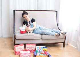 Woman and dog relax on a sofa with gifts