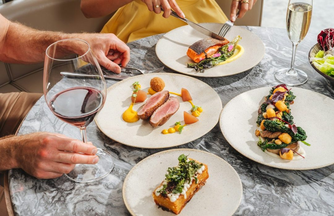 Two people dining on gourmet dishes and wine at a marble table