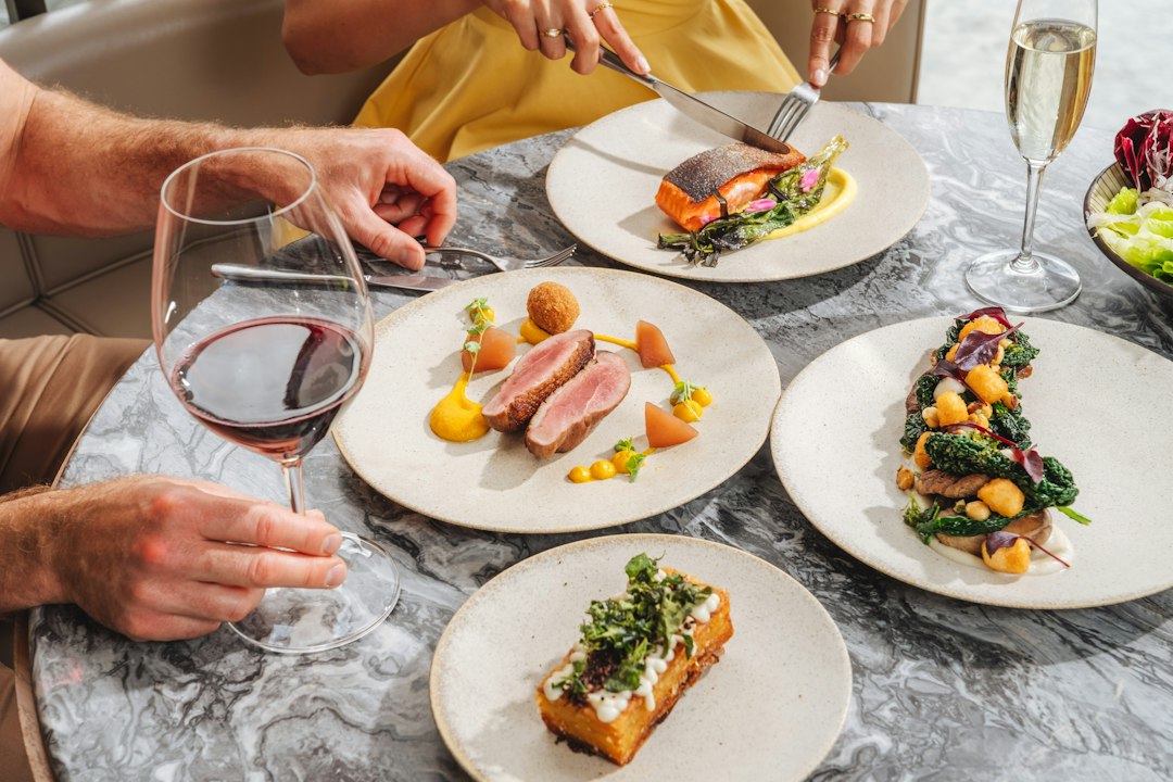 Two people dining on gourmet dishes and wine at a marble table